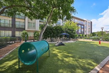 A playground with a green slide and a tent in the background.